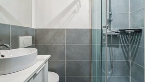 Ein modernes Badezimmer mit Waschbecken, Toilette und einer Duschkabine.