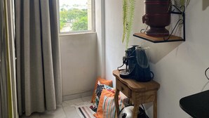 A room with a window, curtains, a hanging plant, a coffee maker, a bag, and a chair. - Carnival… 5 minutes from the subway, Lapa, beaches, Aterro, Sambadrome. (Rio de Janeiro)