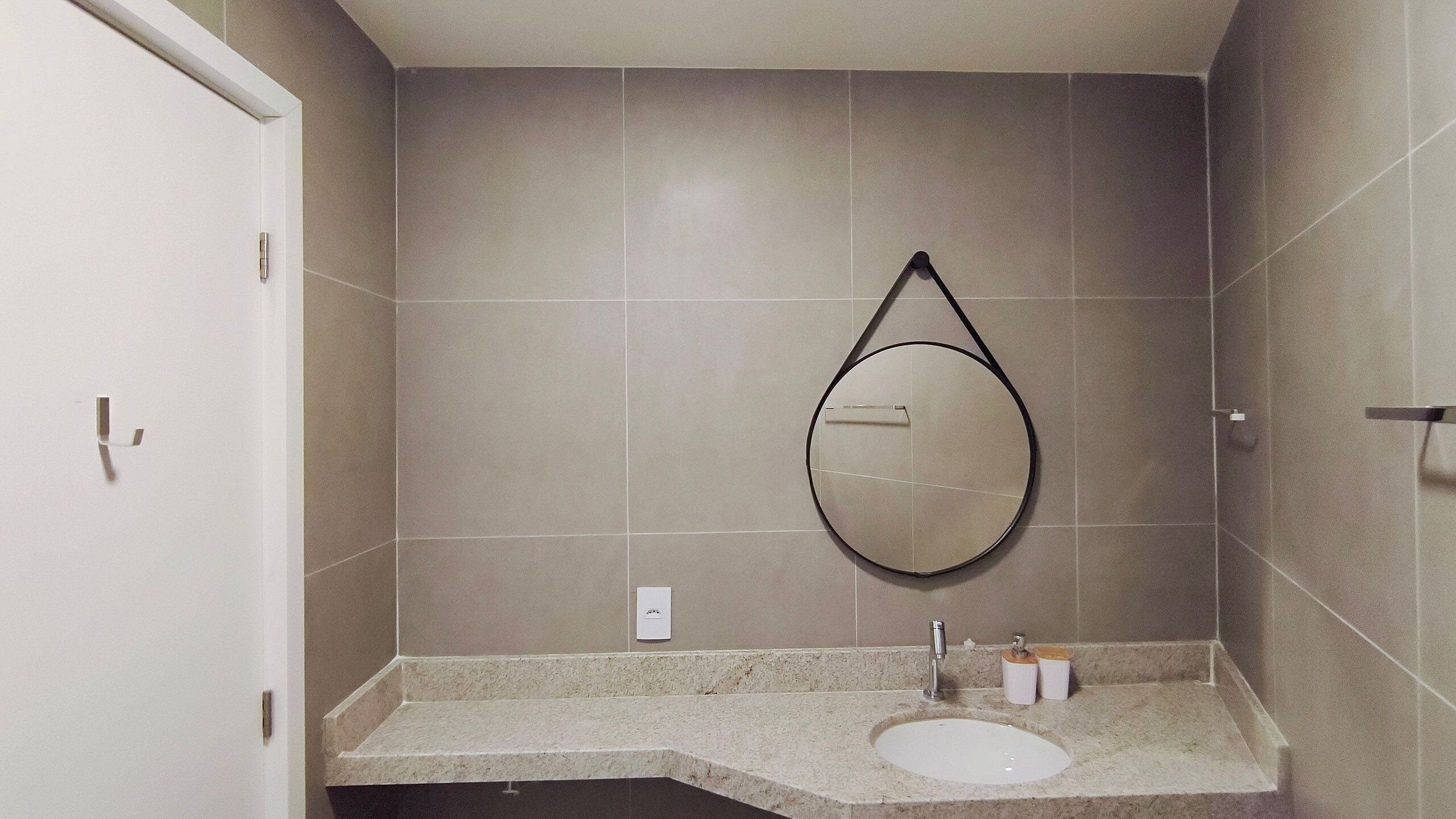 A bathroom with a sink, mirror, and towel rack.
