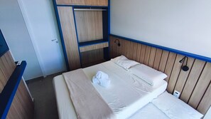 Ein kleiner, kompakter Raum mit Bett, Kleiderschrank und Schreibtisch.
