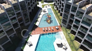 Un edificio moderno con piscina central, zona de estar al aire libre y área de juegos para niños.