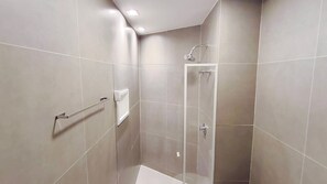 A modern bathroom with a walk-in shower, tiled walls, and a towel rack. - 02 Quartos no Nomar Carneiros Ecoliving (Tamandaré)