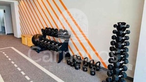 A gym with exercise equipment, a patterned wall, and a carpeted floor. - 02 Quartos no Nomar Carneiros Ecoliving (Tamandaré)