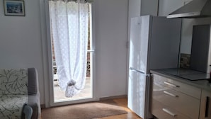 Cozinha compacta com geladeira, fogão e janela com cortina.