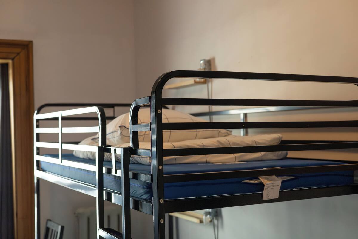 A bunk bed with a blue mattress and a white pillow.