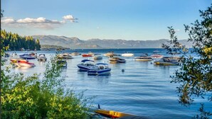 Una marina con diversi natanti ormeggiati, circondata da alberi e montagne sullo sfondo.