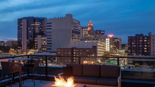 A rooftop terrace with a fire pit, seating area, and a city skyline view. - Luxury 1 BR I Walk to Mayo Skyway I Pets I Parking (Rochester)