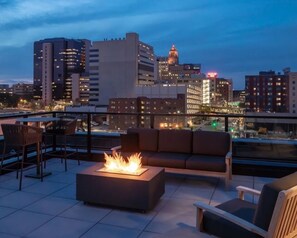 Una terrazza sul tetto con un braciere, un'area salotto e vista sullo skyline della città.