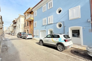 A street with parked cars and a building with multiple windows and balconies. - P075 - Porto Recanati, new two-room apartment facing the sea with direct beach access (Porto Recanati)