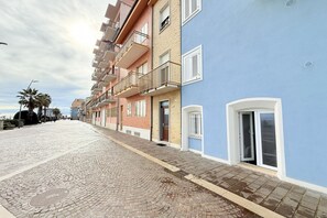 A cobblestone street lined with multi-story buildings, balconies, and a clear sky. - P075 - Porto Recanati, new two-room apartment facing the sea with direct beach access (Porto Recanati)