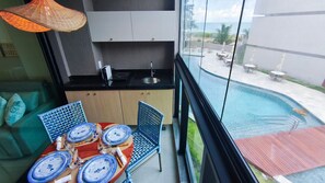 Ein Balkon mit Essplatz und Blick auf Pool und Meer.