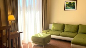 Una habitación con sofá, reposapiés, lámpara y un cuadro en la pared.