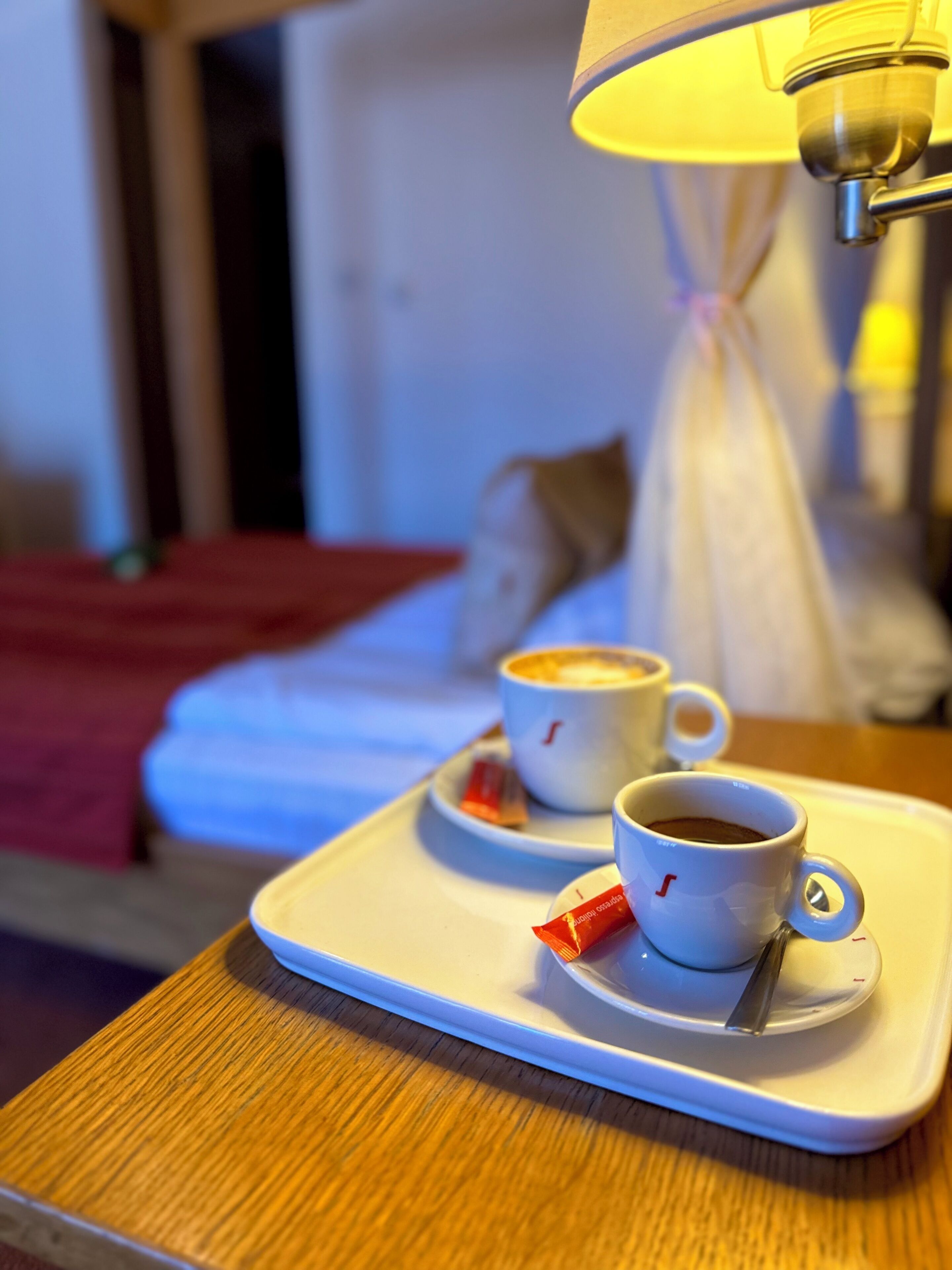 Un plateau avec deux tasses de café et un sachet de crème liquide, posé sur une table en bois.