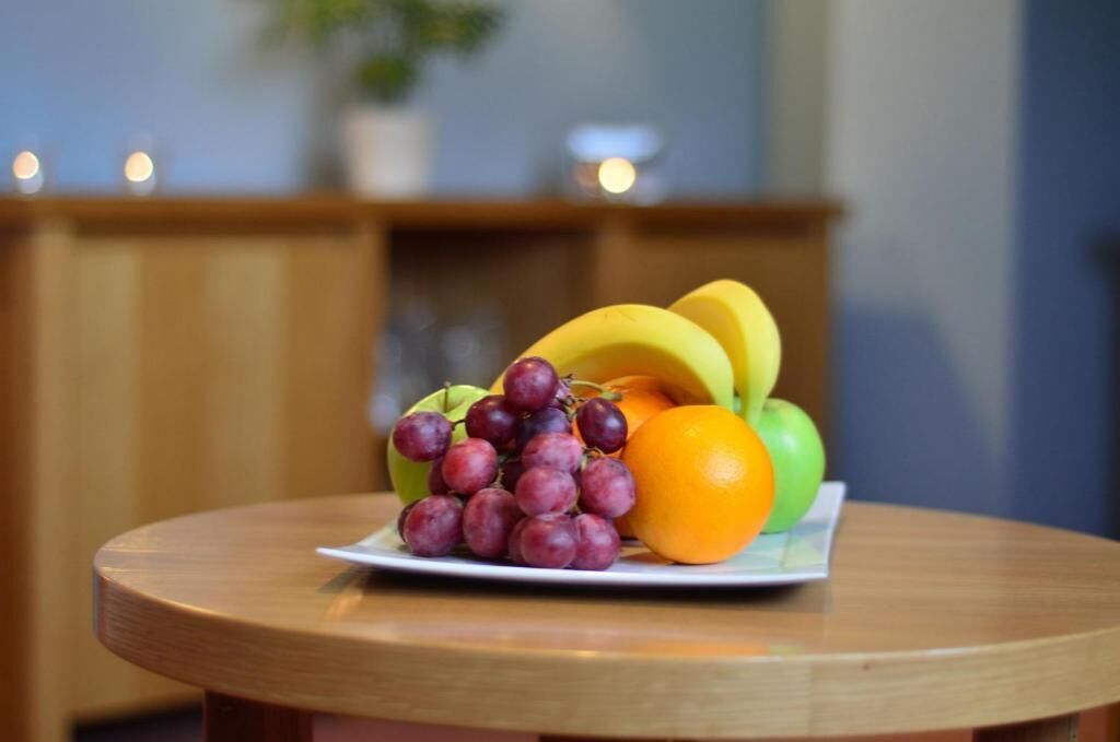 Un plato de fruta sobre una mesa redonda con un fondo de madera.