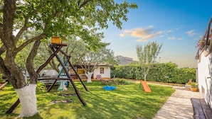 Un jardin avec une balançoire, un petit abri de jardin et un espace patio.
