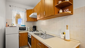 Une cuisine de taille réduite, dotée de meubles en bois, d’un four à micro-ondes, d’un évier et d’une cuisinière.