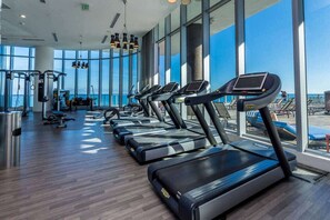 A gym with treadmills, exercise equipment, and large windows overlooking a beach. - 1BR Haven | Pool & Ocean | WC Miami Stadium Trip (Hollywood)