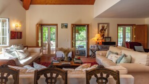 Uma sala de estar espaçosa com teto de madeira, um conjunto de sofás, uma mesa de centro e uma mesa de jantar.