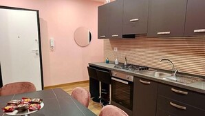 A compact kitchen with a dining area, featuring a stove, sink, and a small round mirror on the wall. - MARILU' ACCOGLIENZA DEL SUD (Foggia)
