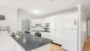 A modern kitchen with white cabinetry, a granite countertop, and a built-in oven. - Skye at Lighthouse, 2 Skye Court (Port Macquarie)