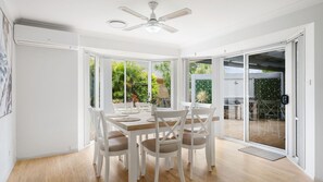 A dining area with a table and chairs, a ceiling fan, and a view of the outdoors. - Skye at Lighthouse, 2 Skye Court (Port Macquarie)