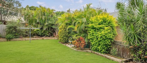 Un giardino curato con prato, siepi e recinzione in legno.