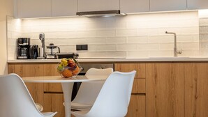 Cozinha moderna com armários brancos, bancada de madeira e uma área de jantar com cadeiras brancas e uma mesa redonda.