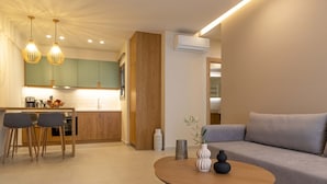 A modern living room with a sofa, a round coffee table, and a dining area with chairs and a table. - Olivevine4 (Nafplio)