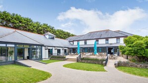 A modern building with a glass facade, outdoor seating area, and a stone pathway. - Landal Bude Coastal Resort (Bude)