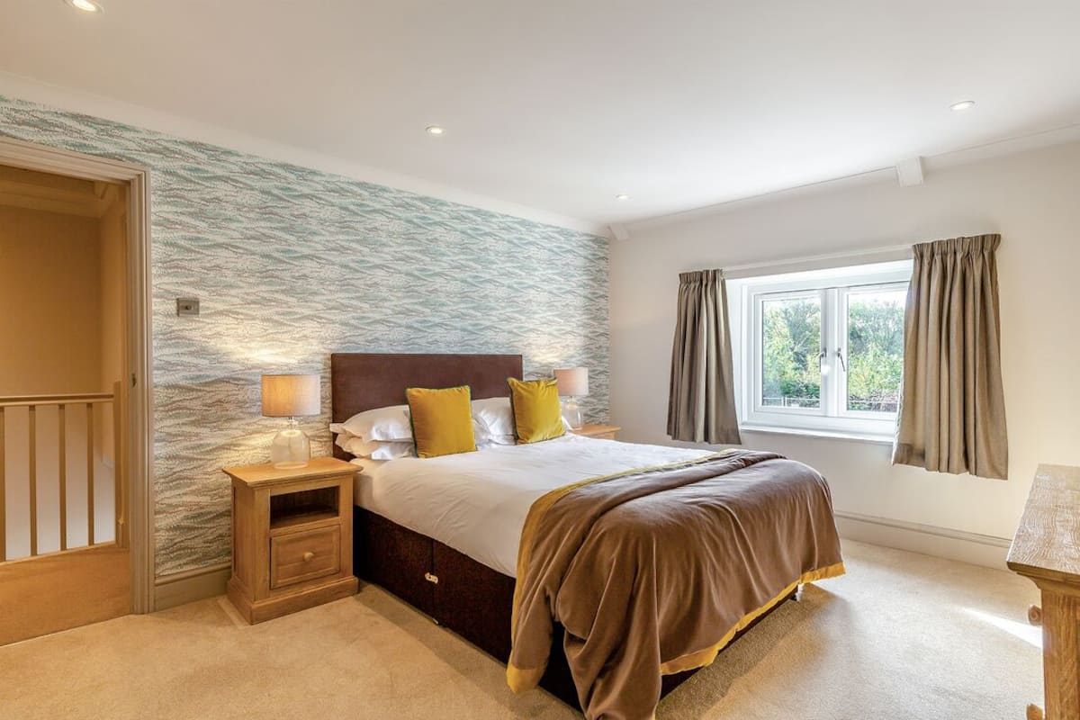 A bedroom with a bed, nightstand, and window with curtains.