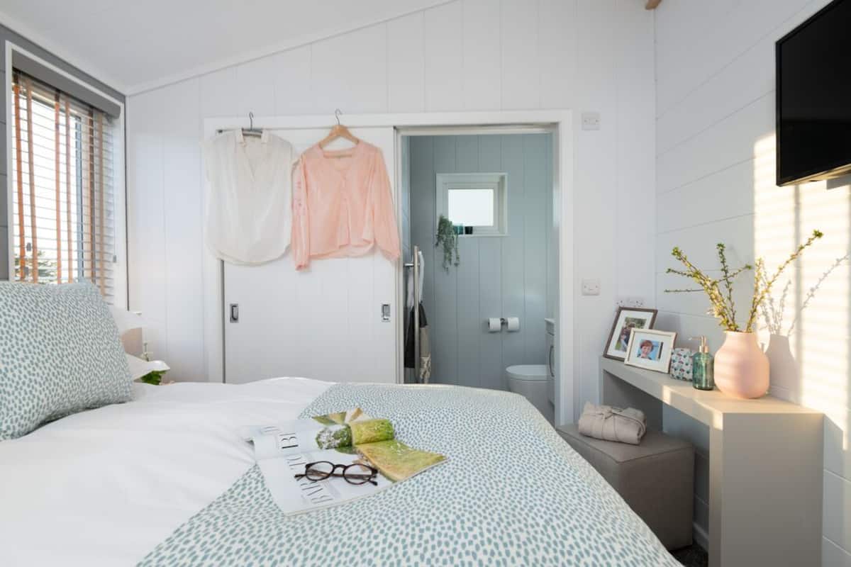 A bedroom with a bed, a bedside table, a wardrobe, and a bathroom visible through an open door.