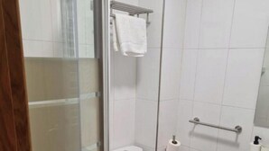 Et moderne badeværelse med bruseniche i glas, toilet og vask med spejl.
