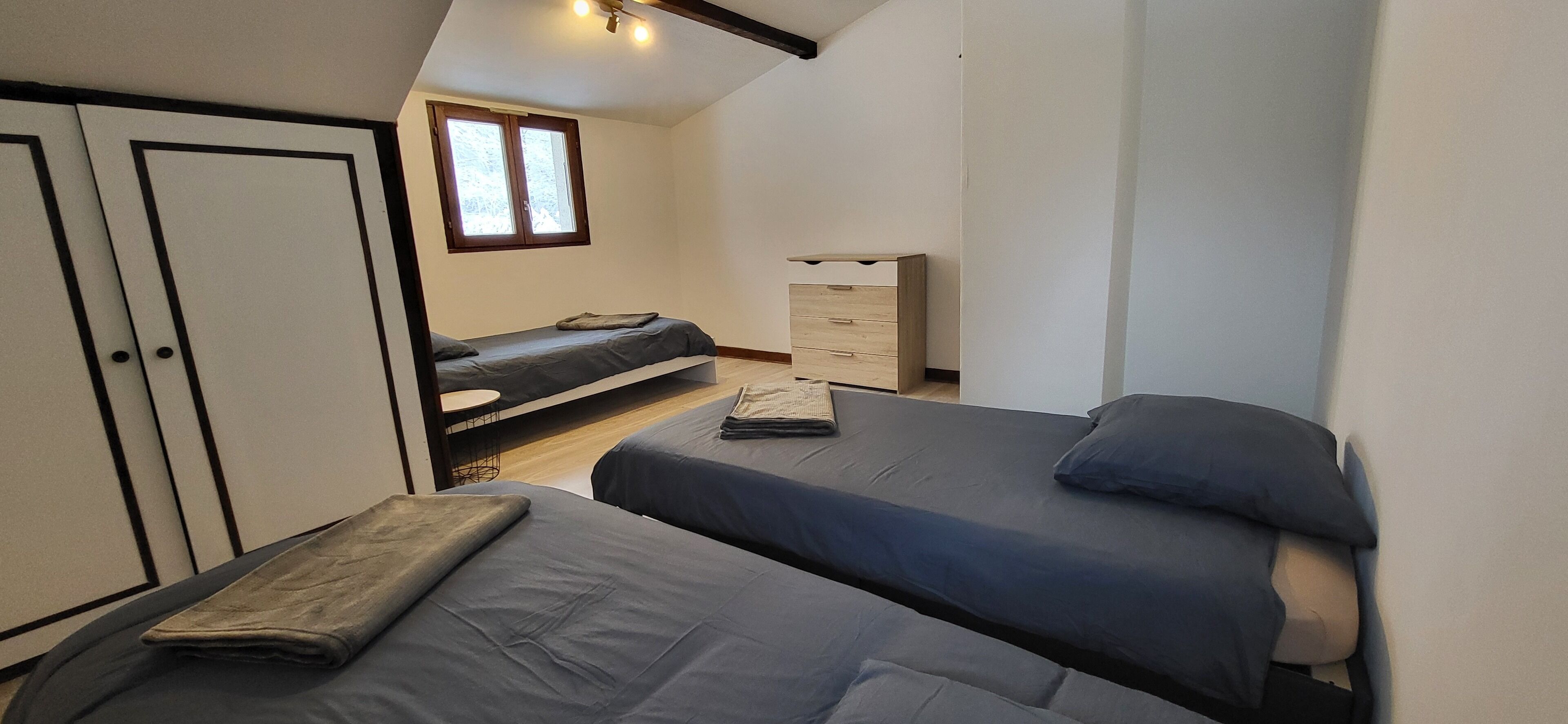 Un dormitorio con dos camas, un armario, un escritorio y una ventana.