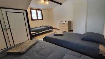 Un dormitorio con dos camas, un armario, un escritorio y una ventana.