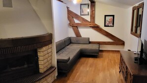 A cozy living room with a fireplace, a wooden staircase, and a gray sectional sofa. - Wonderful 2-bedroom apartment in Évette-Salbert perfect for relaxing stay (Évette-Salbert)