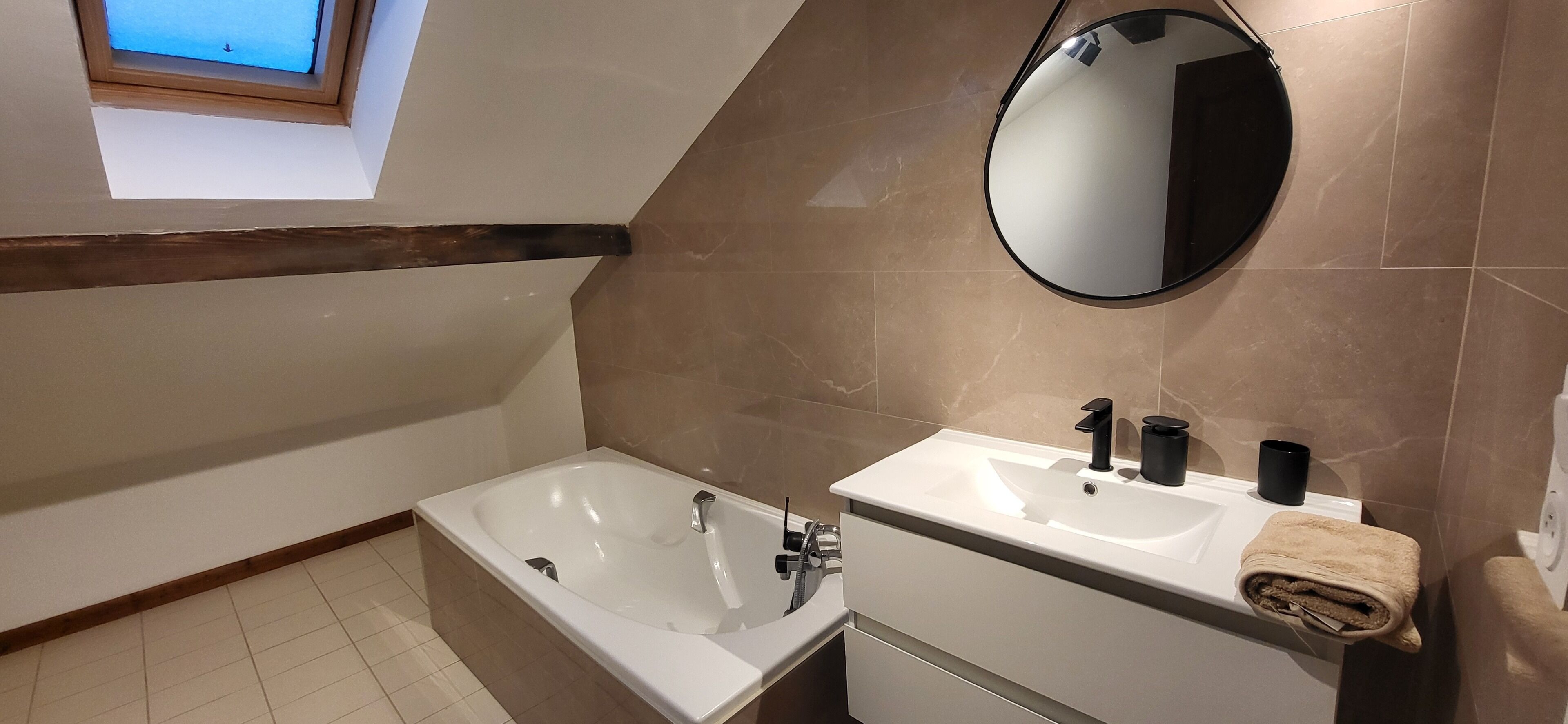 A modern bathroom with a bathtub, two sinks, a mirror, and a towel rack.