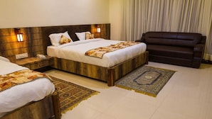 A hotel room with a large bed, a smaller bed, a sofa, and two wall-mounted lamps. - Sanjay Resort Baghela Heritage (Majhauli)