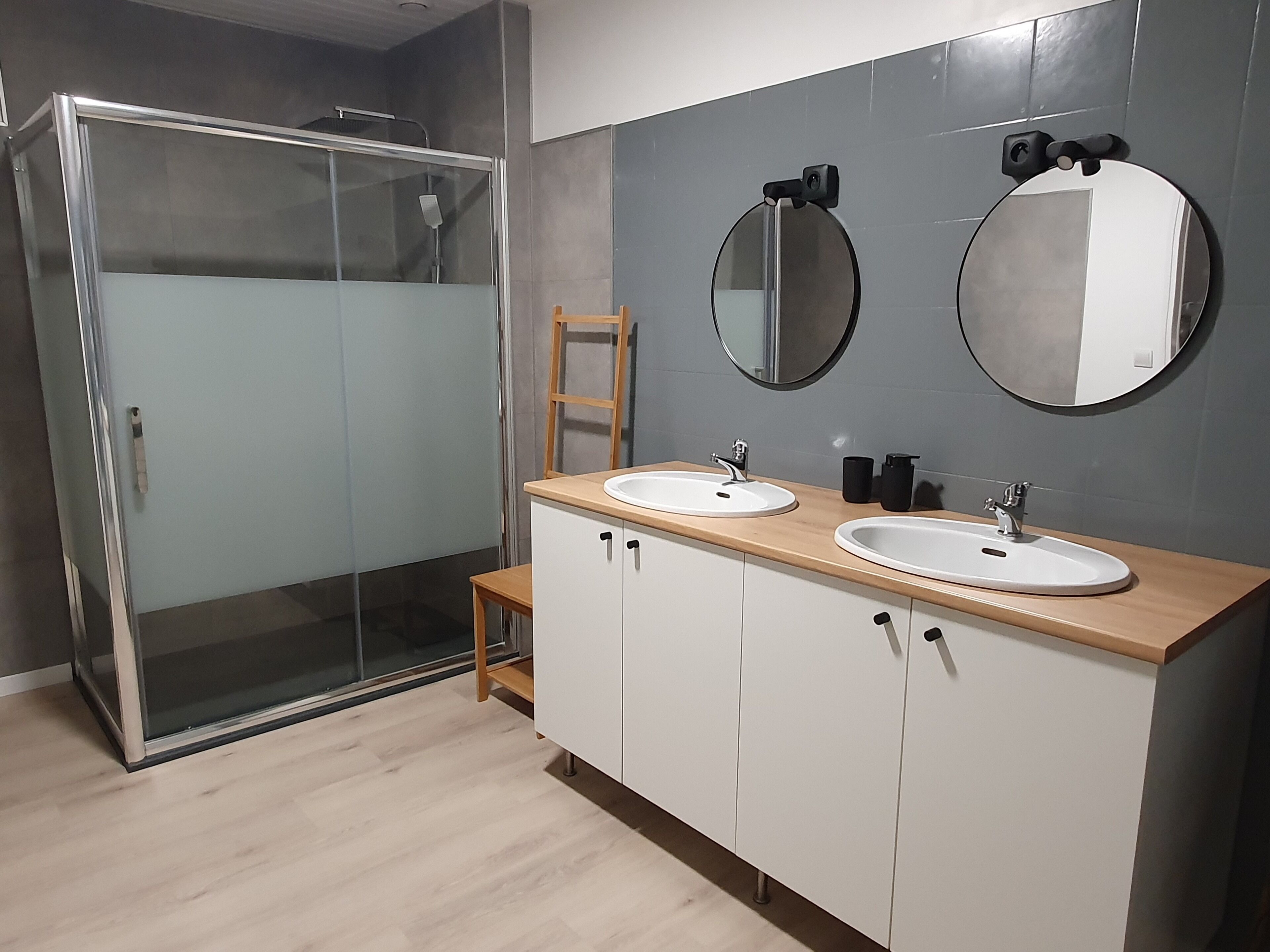 Une salle de bain moderne avec deux vasques, une douche en verre et un meuble-lavabo en bois.