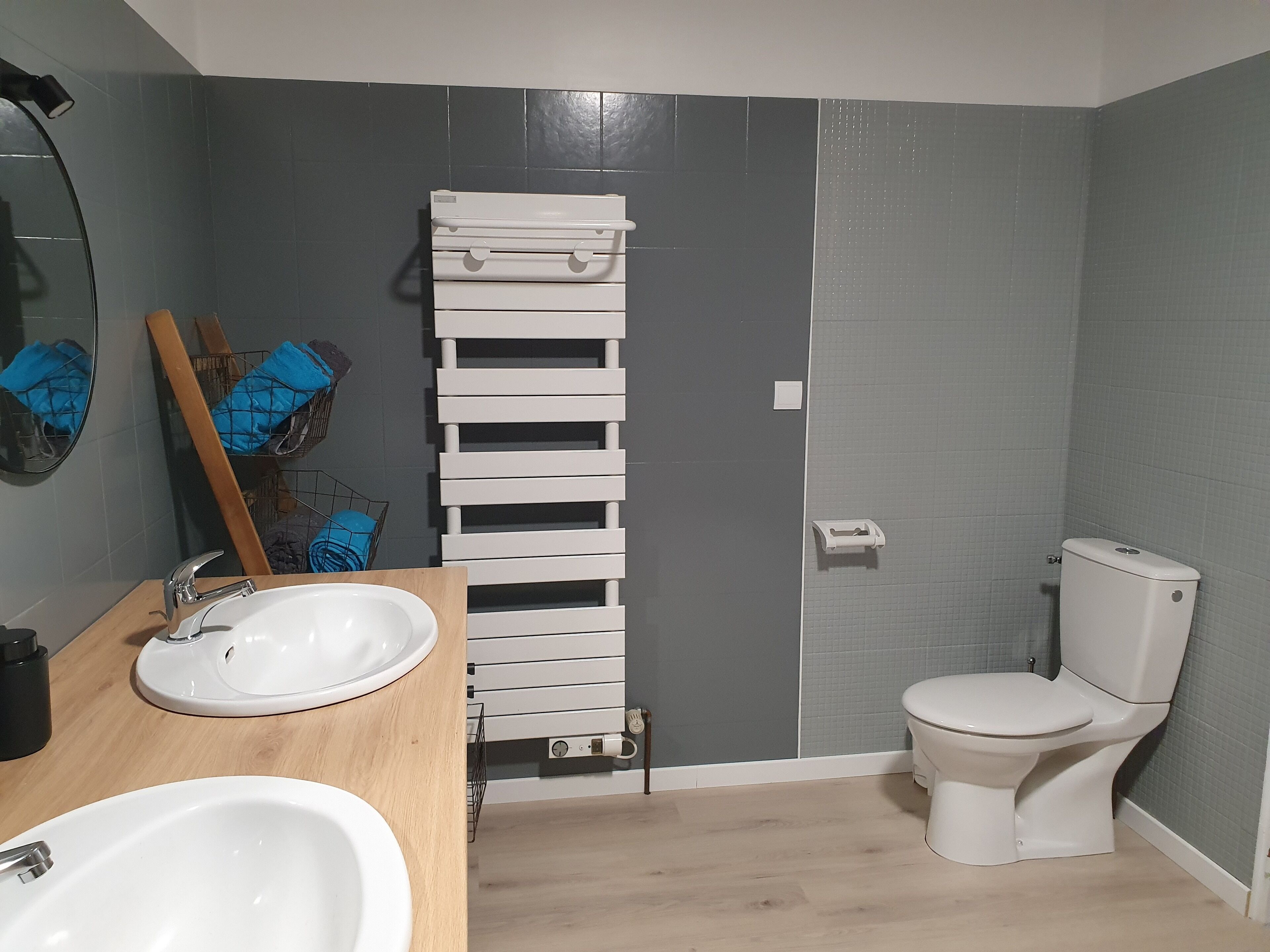 Ein Badezimmer mit Holzwaschtisch, Waschbecken, Spiegel, Handtuchhalter, Toilette und Duschbereich.