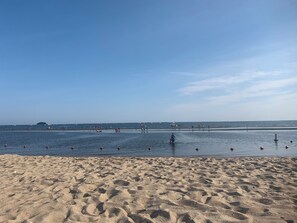 En sandstrand med et roligt hav og en klar himmel.