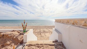A beach view with a white building and a decorative plant. - Casa Puesta del Sol – Beachfront, Rocky Point (Puerto Peñasco)