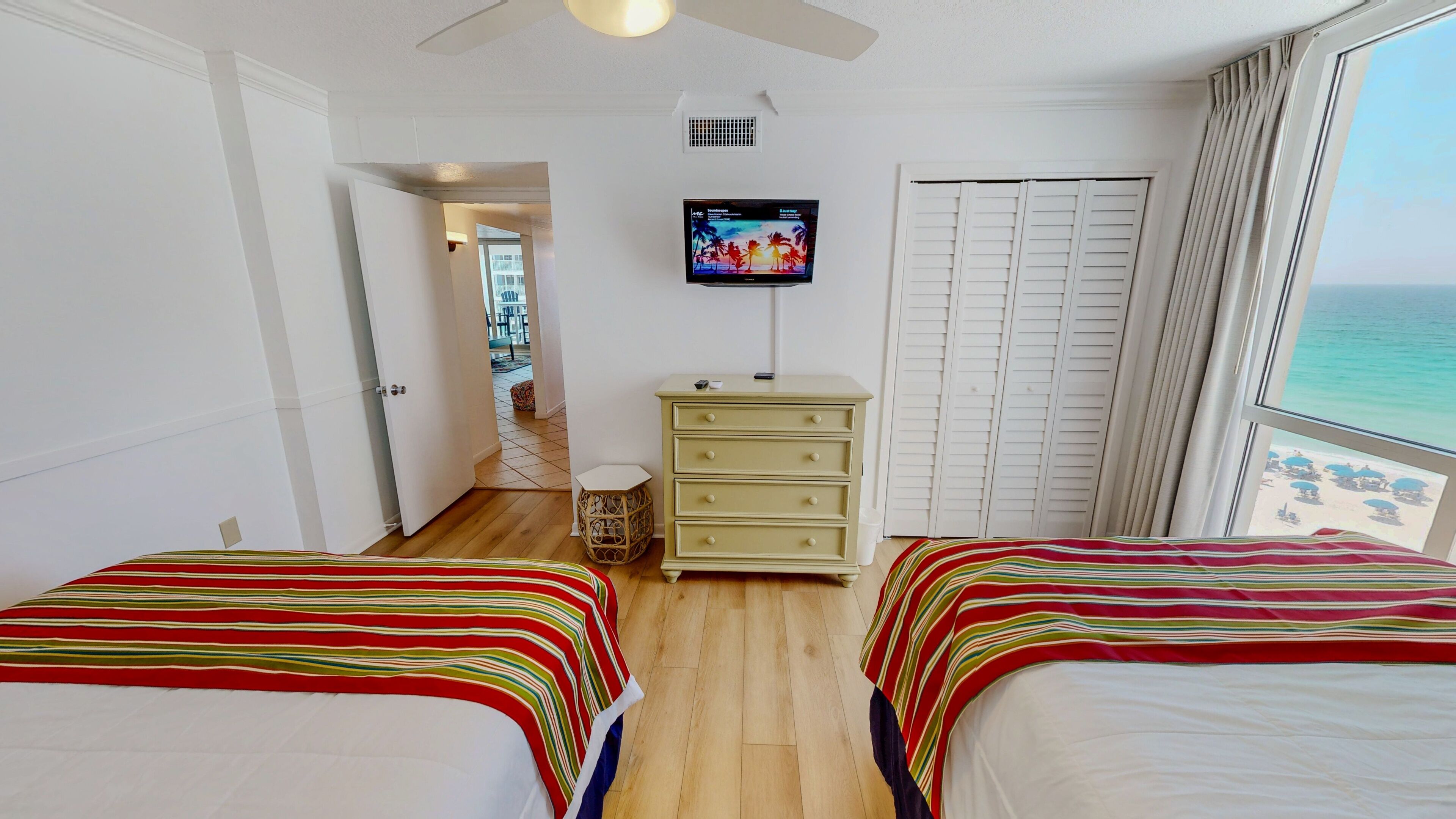 Une chambre d’hôtel avec deux lits, une télévision, une commode et une vue sur l’océan.