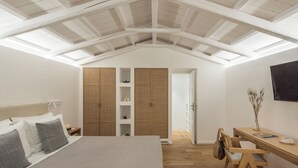 Un dormitorio con techo inclinado, una cama con almohadas, un escritorio de madera y un armario.