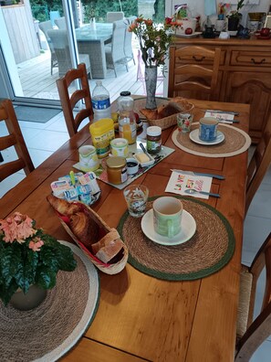 Ein Esstisch, reichhaltig gedeckt mit Speisen, Besteck und einer Blumenvase.