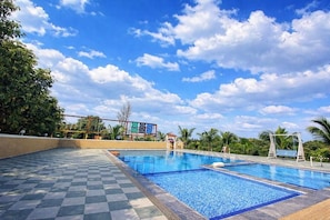 Ein Pool mit Schachbrettmuster, umgeben von Palmen und blauem Himmel.