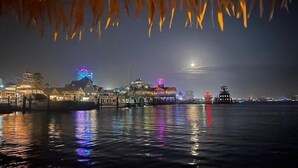 Une scène nocturne le long du front de mer, avec des bâtiments illuminés et une pagode traditionnelle.