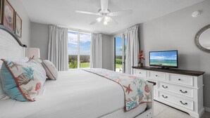 Une chambre à coucher avec un lit, une télévision, une commode et un ventilateur de plafond.