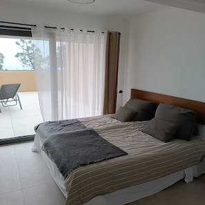 Une chambre à coucher avec un lit, une chaise et une vue sur l’extérieur.