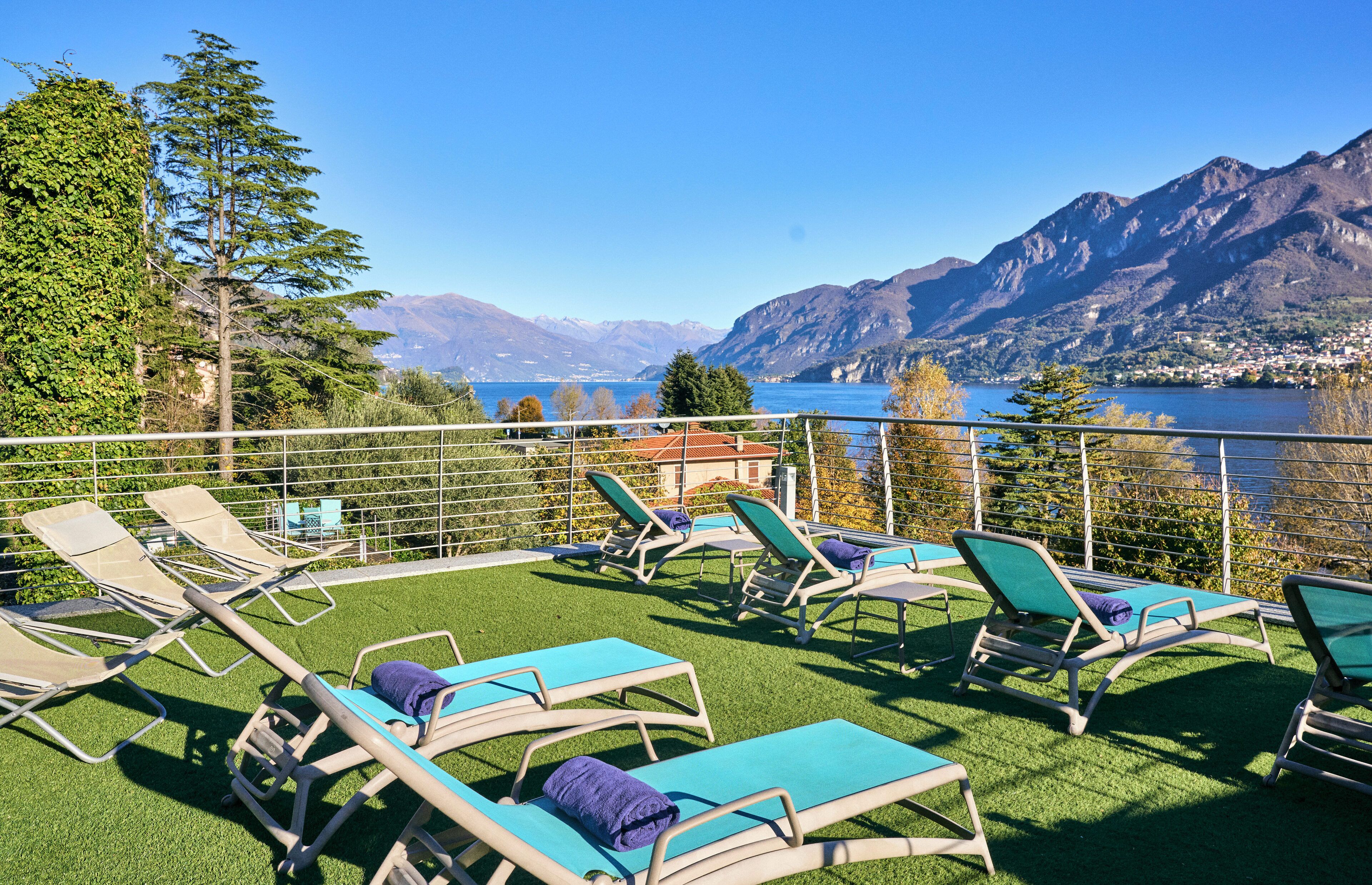 Eine Terrasse mit Liegestühlen und Blick auf Berge und einen See.