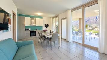 A modern kitchen with white cabinets and a heart-shaped decoration, a dining area with a table and chairs, and a view of mountains through large sliding glass doors.